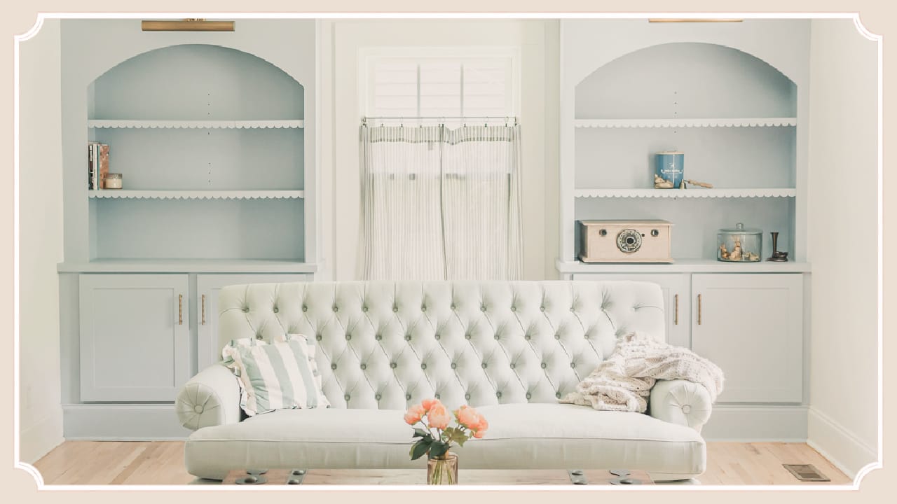 Sitting room at The Cottage at Foxhavens featuring original built-in bookcases, a tufted sofa, and soft morning light.