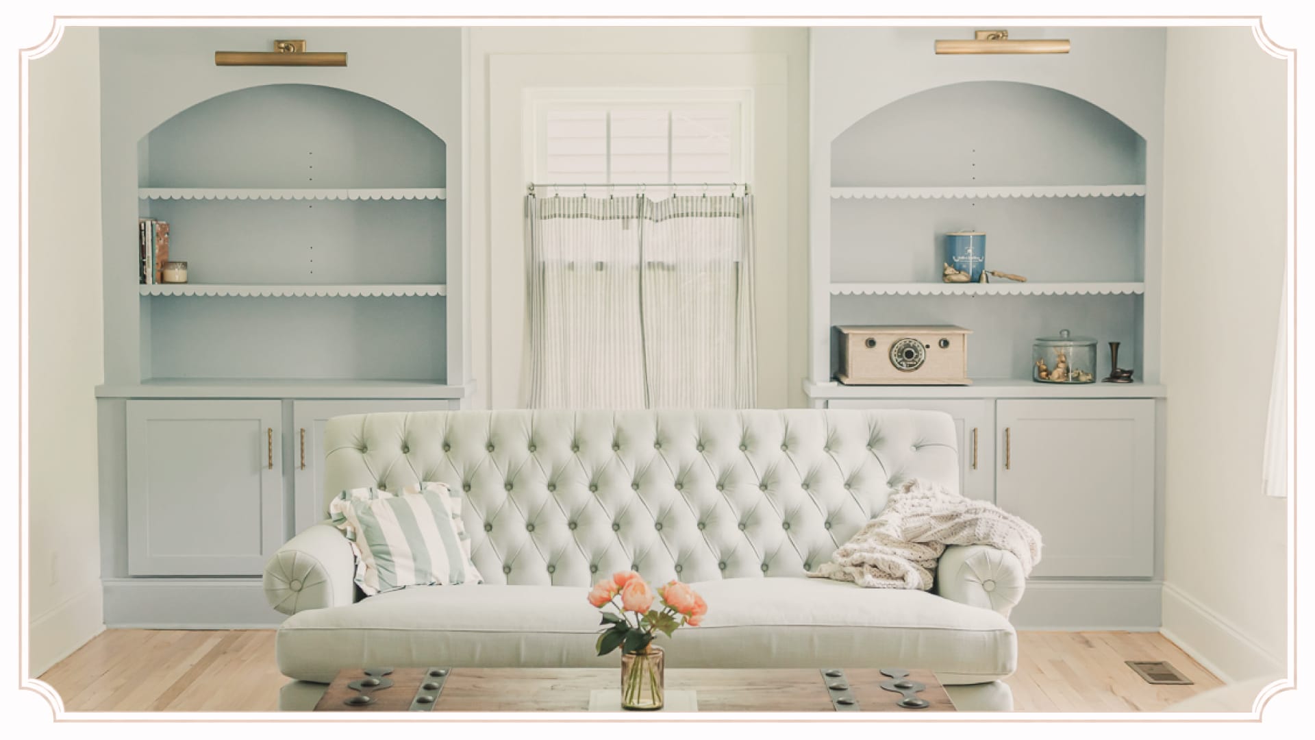 Sitting room at The Cottage at Foxhavens featuring original built-in bookcases, a tufted sofa, and soft morning light.
