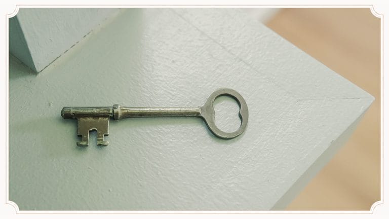 Original brass skeleton key from the 1945 cottage resting on a windy blue bookcase